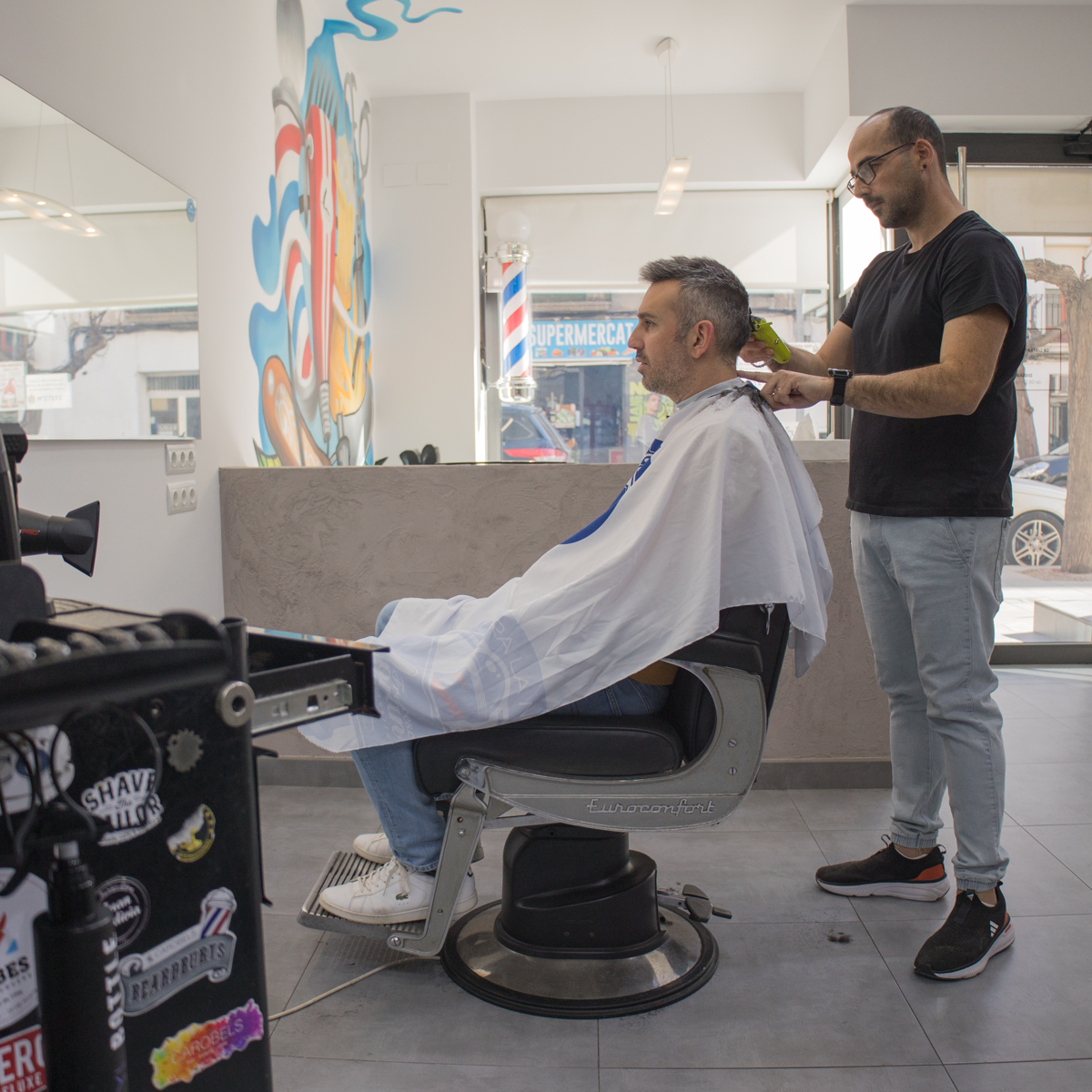 Peluquero cortando el pelo a un chico en una peluquería.